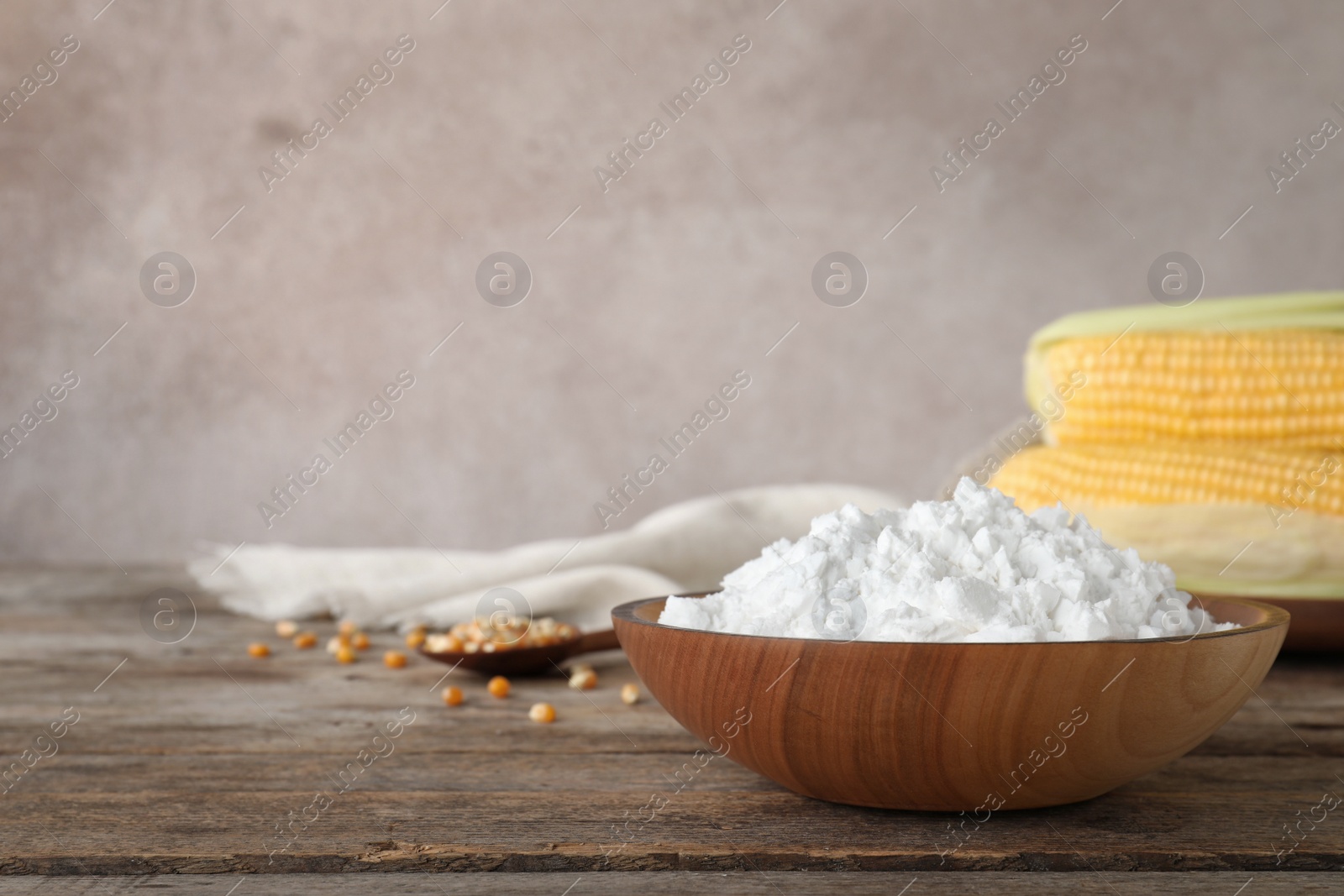 Photo of Bowl with corn starch on wooden table. Space for text