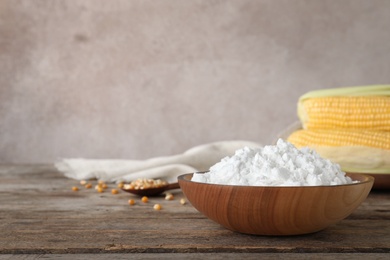 Photo of Bowl with corn starch on wooden table. Space for text