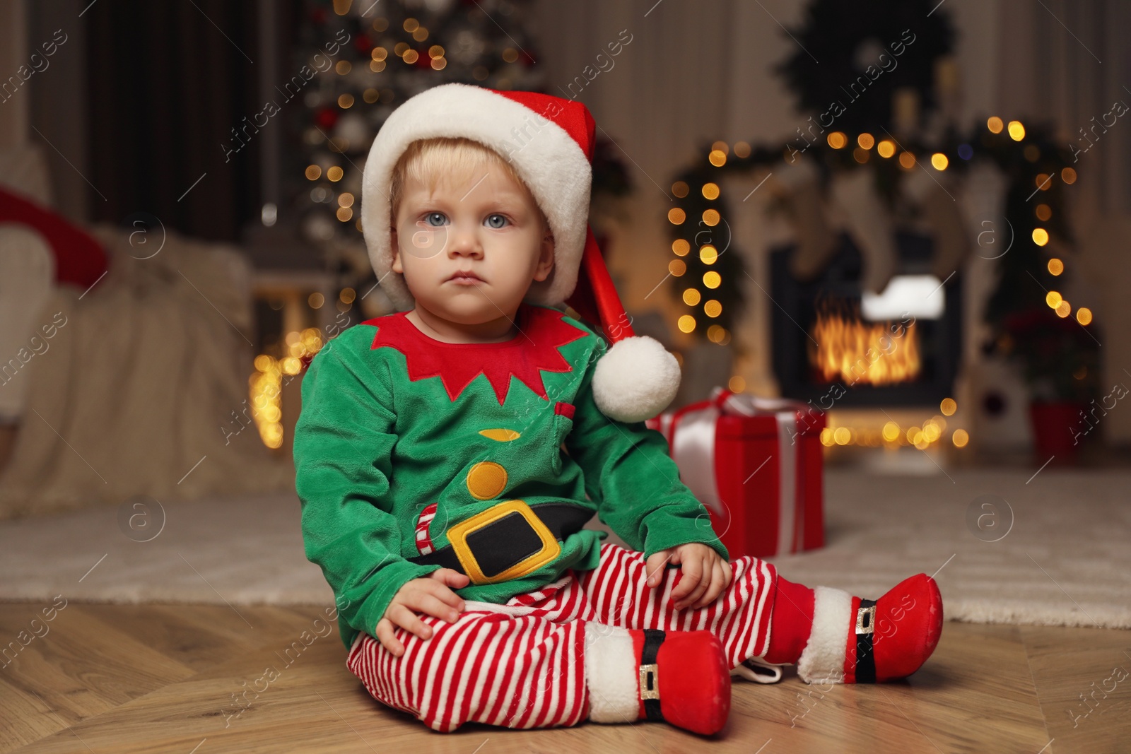 Photo of Cute baby in Santa's elf clothes at home. Christmas suit
