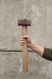 Photo of Man with sledgehammer near grey wall, closeup