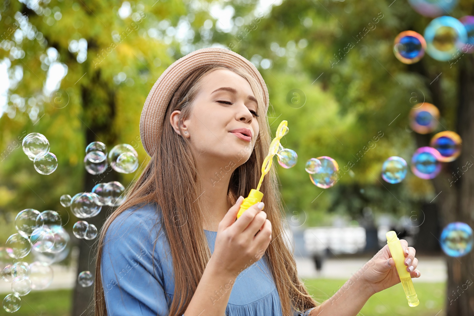 Photo of Young woman blowing soap bubbles in park