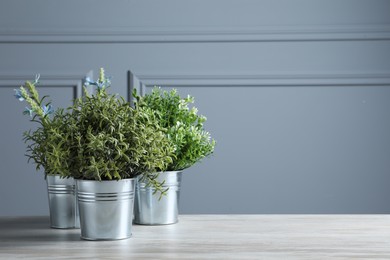 Different aromatic potted herbs on white wooden table, space for text