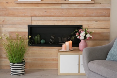 Stylish living room interior with burning candles on table