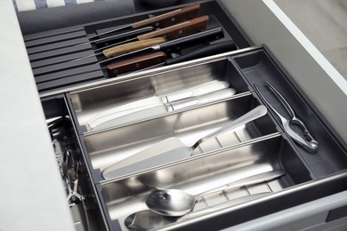 Open drawer of kitchen cabinet with different utensils and cutlery, closeup