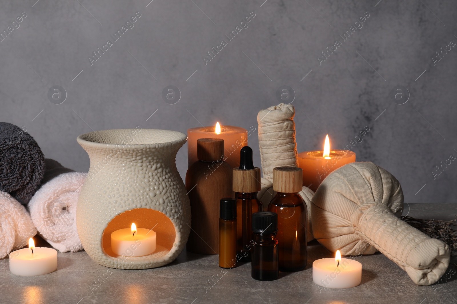 Photo of Aromatherapy. Scented candles and spa products on gray textured table