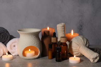 Photo of Aromatherapy. Scented candles and spa products on gray textured table