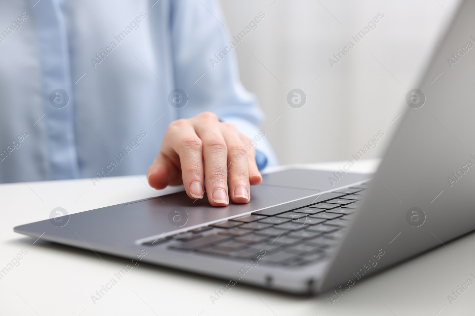 Photo of E-learning. Woman using laptop at white table indoors, closeup