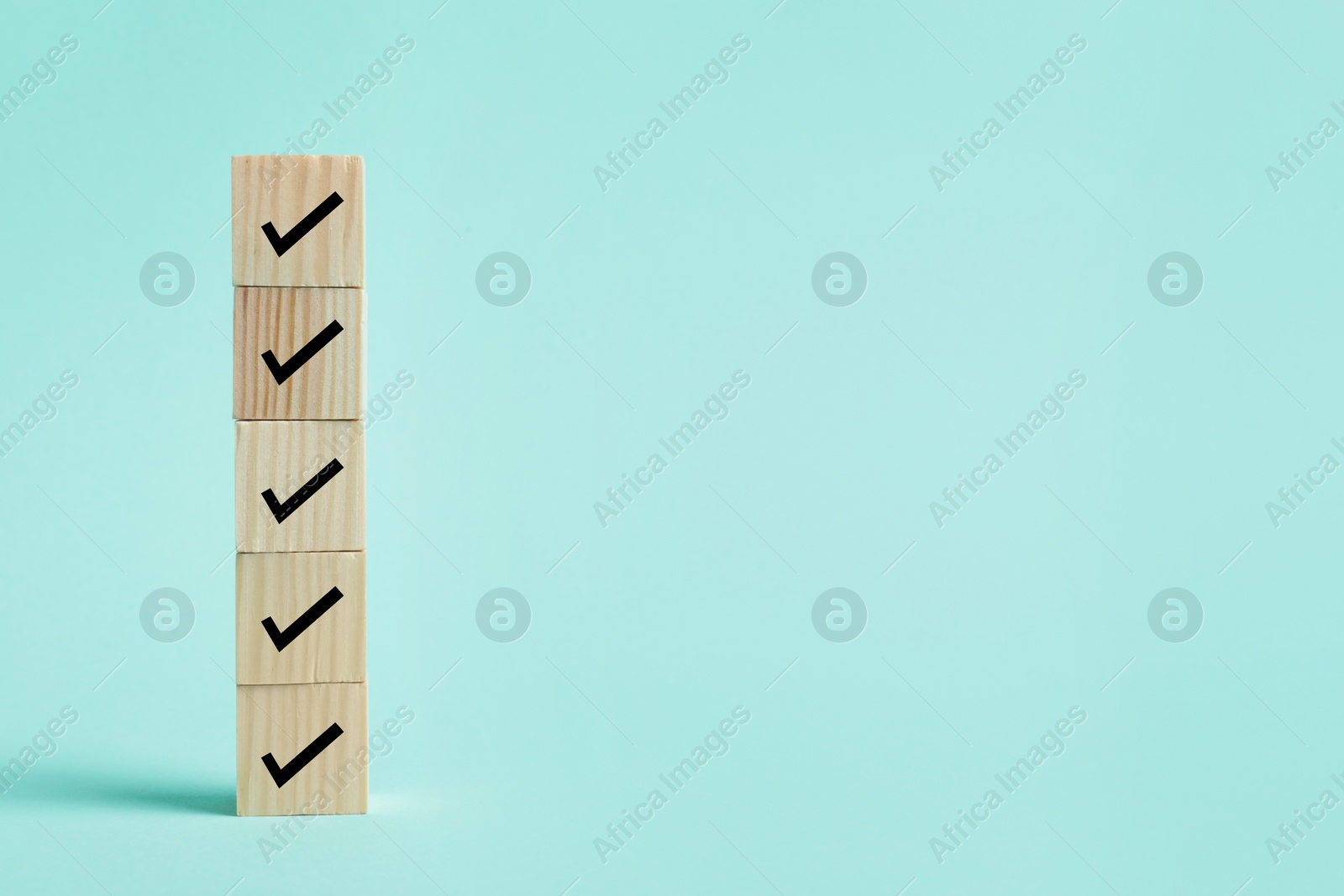 Image of Stacked wooden cubes with check marks on turquoise background. Space for text