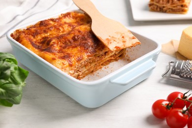 Delicious lasagna in baking dish on white table