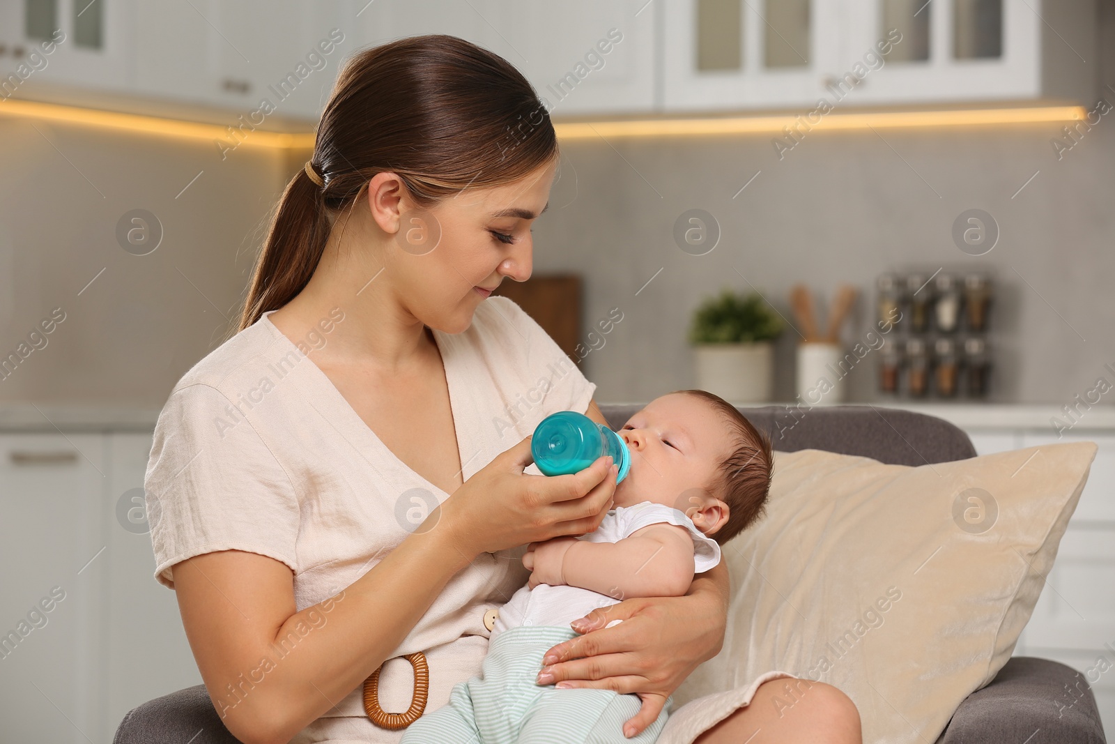 Photo of Mother feeding her cute child with infant formula indoors