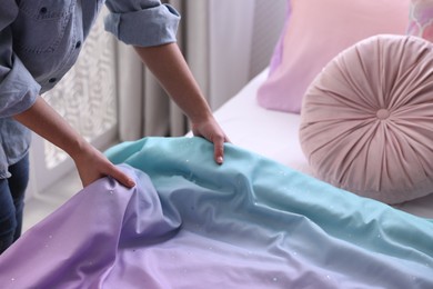 Woman making bed with new linens in children's room, closeup. Modern interior design