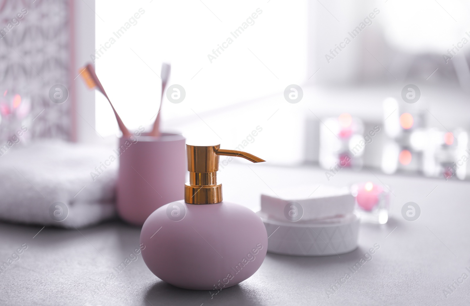 Photo of Bottle with liquid soap and toiletries on table against blurred background. Space for text
