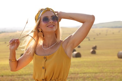 Beautiful happy hippie woman with spikelets in field