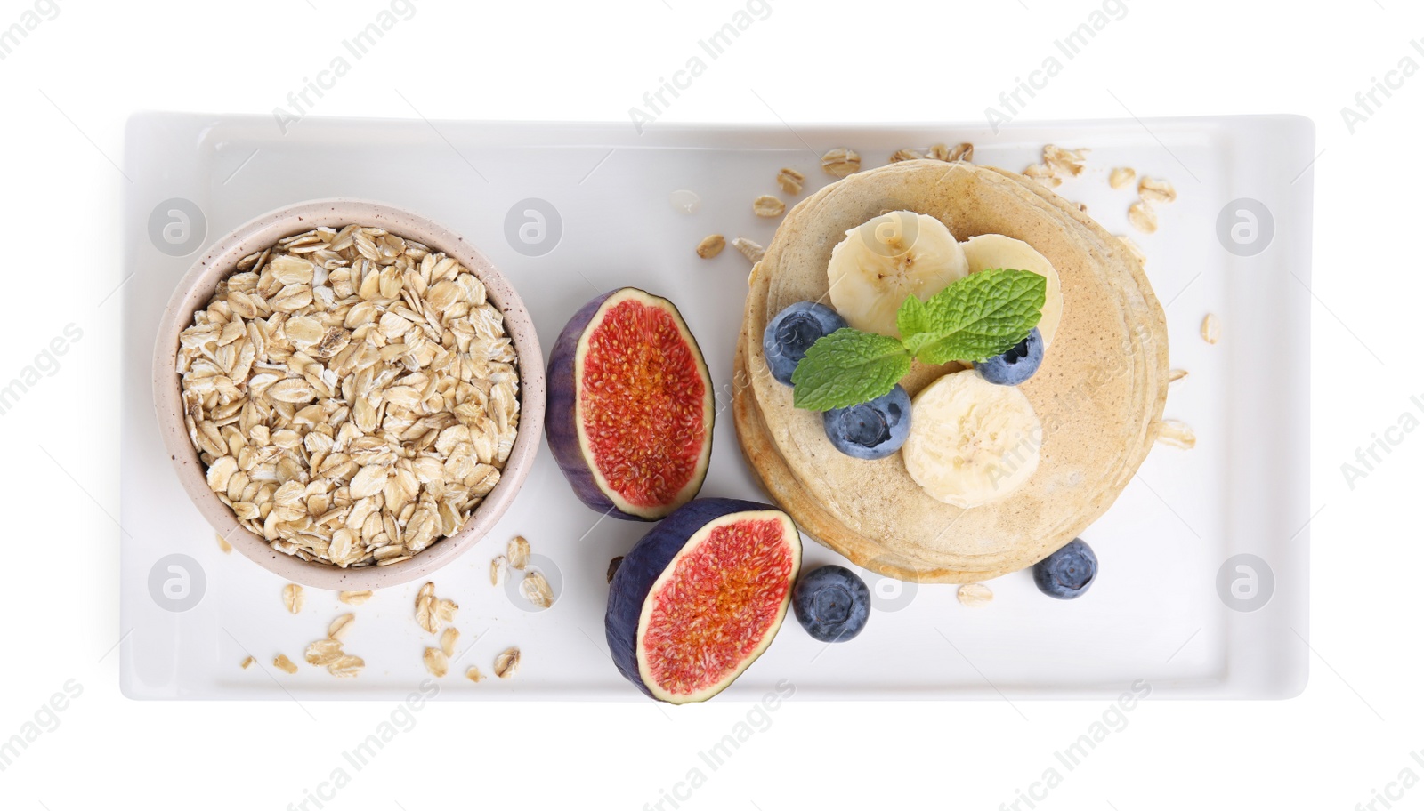 Photo of Tasty oatmeal pancakes and ingredients on white background, top view