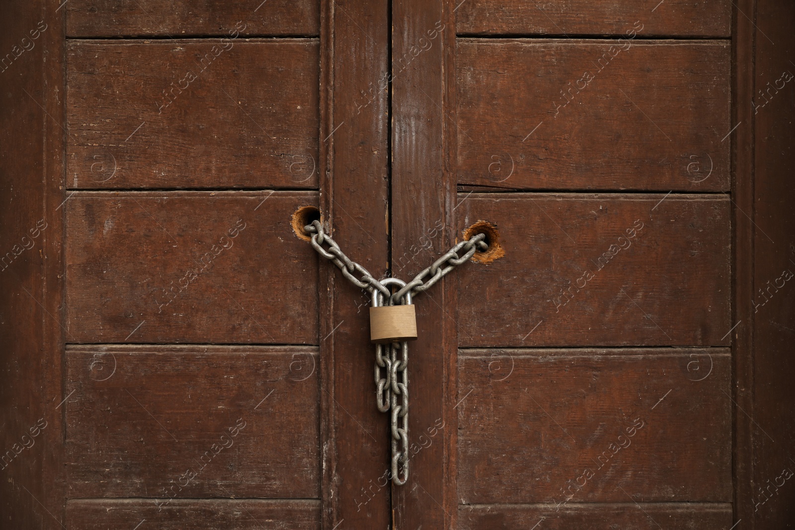 Photo of Old wooden door with chain and lock, closeup view