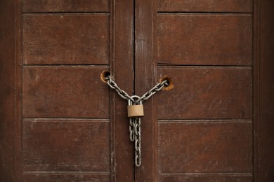 Old wooden door with chain and lock, closeup view