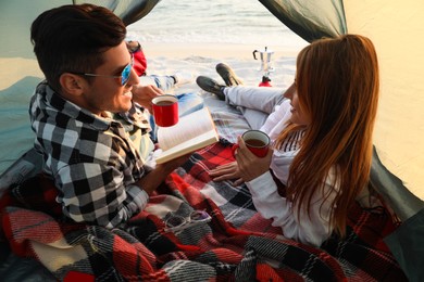 Photo of Couple resting in camping tent near sea