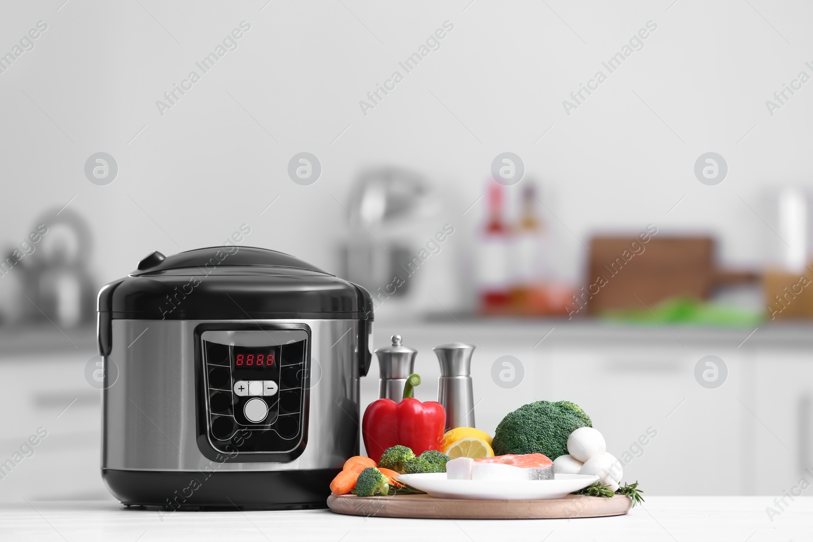 Photo of Modern multi cooker and products on table in kitchen. Space for text