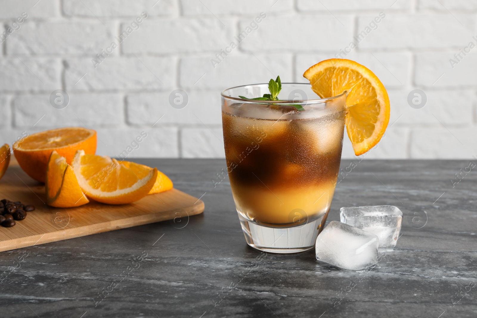 Photo of Tasty refreshing drink with coffee and orange juice on grey marble table, space for text