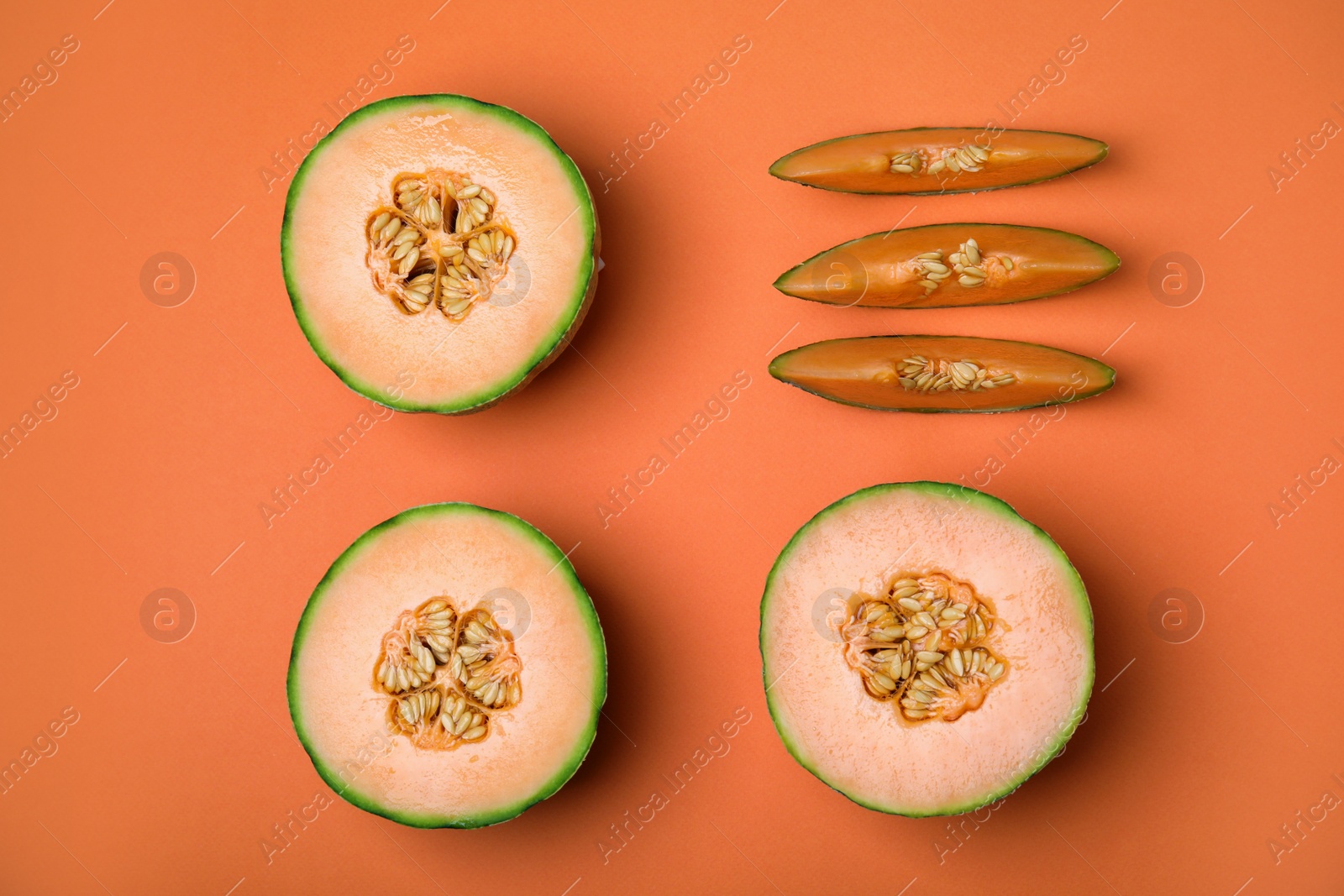 Photo of Cut different types of melons on orange background, flat lay