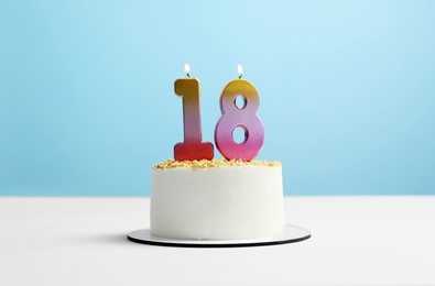 Photo of Coming of age party - 18th birthday. Delicious cake with number shaped candles on light blue background