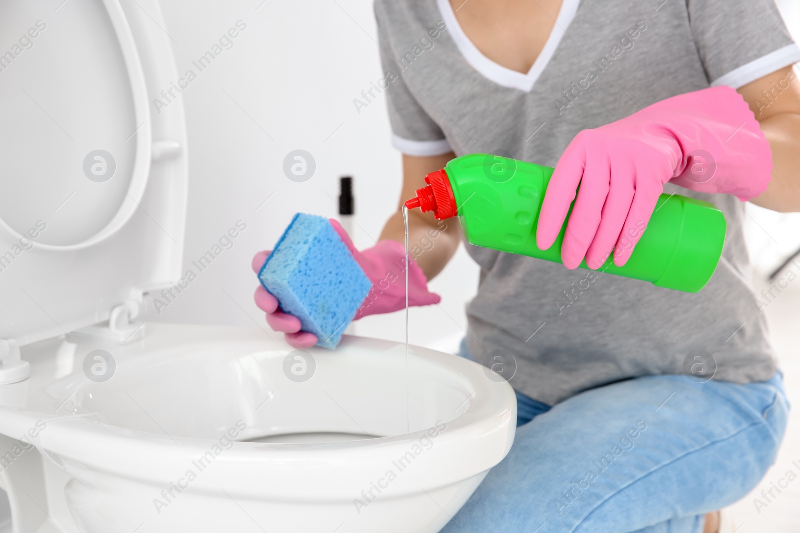 Photo of Woman cleaning toilet bowl in bathroom