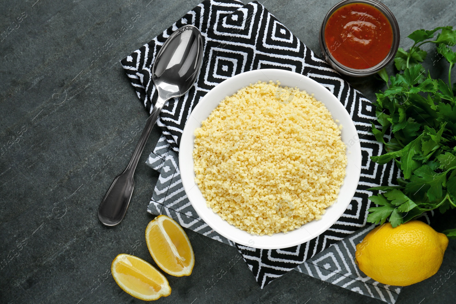 Photo of Tasty couscous and ingredients on grey table, flat lay. Space for text