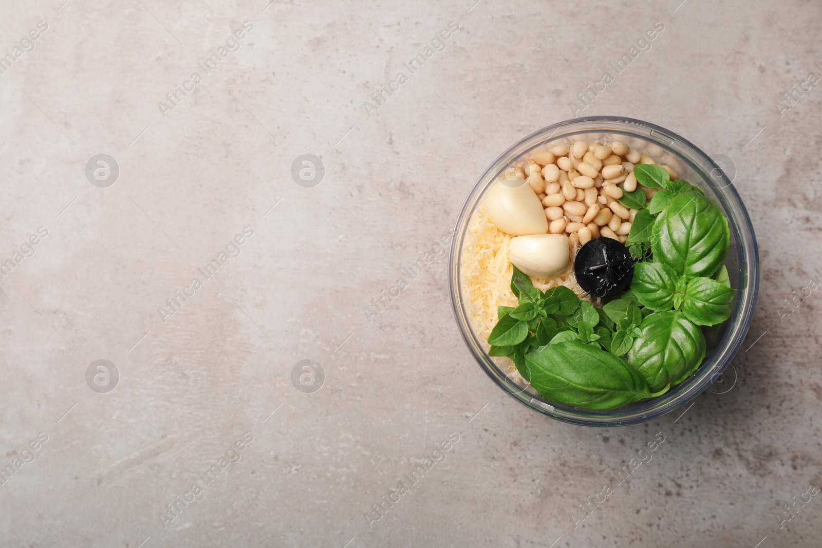 Photo of Ingredients for homemade basil pesto sauce in blender container on table, top view. Space for text