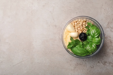 Photo of Ingredients for homemade basil pesto sauce in blender container on table, top view. Space for text