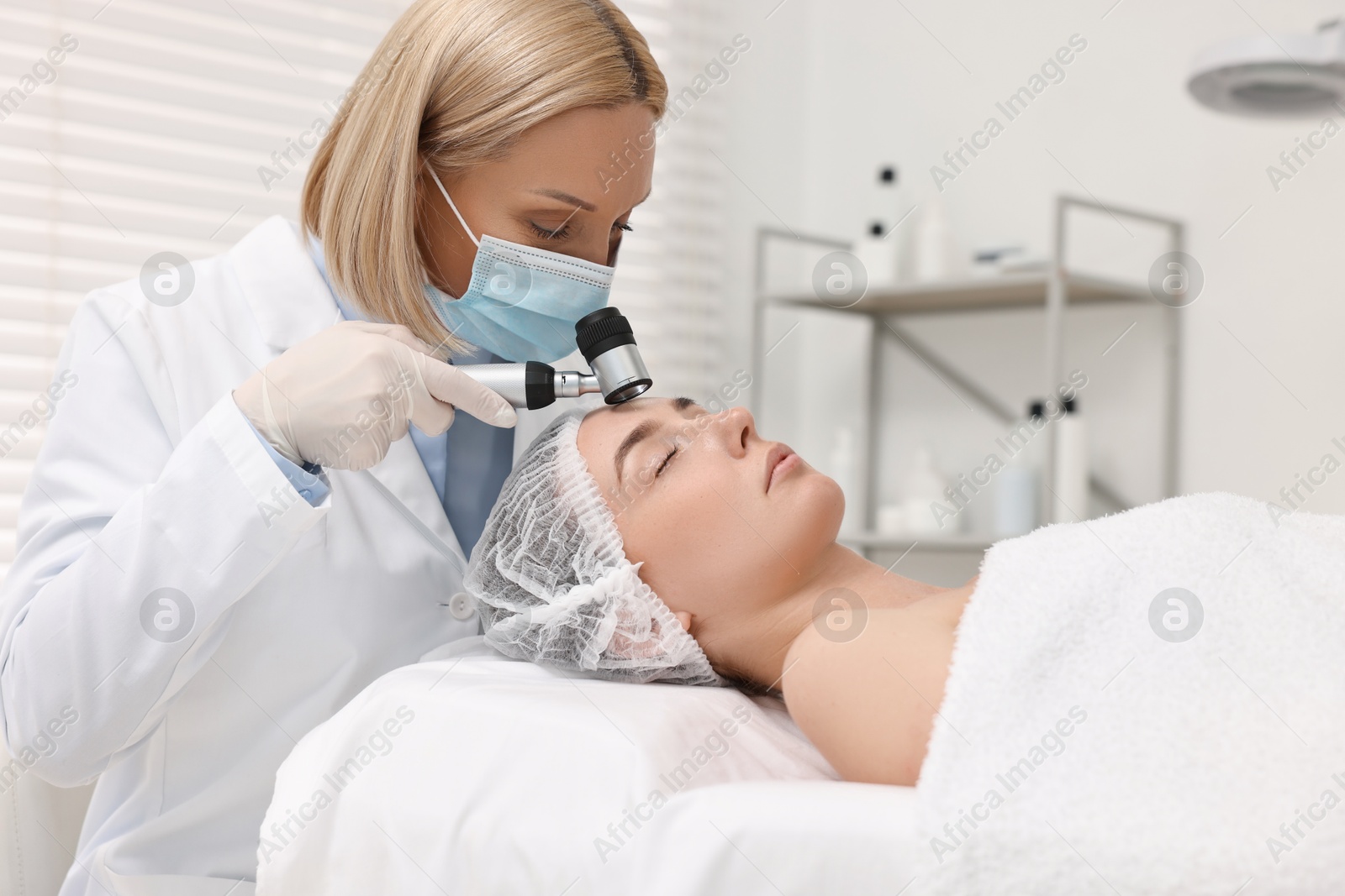 Photo of Dermatologist with dermatoscope examining patient`s face in clinic