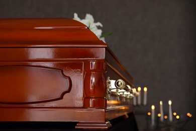 Photo of Wooden casket with white lilies in funeral home, closeup