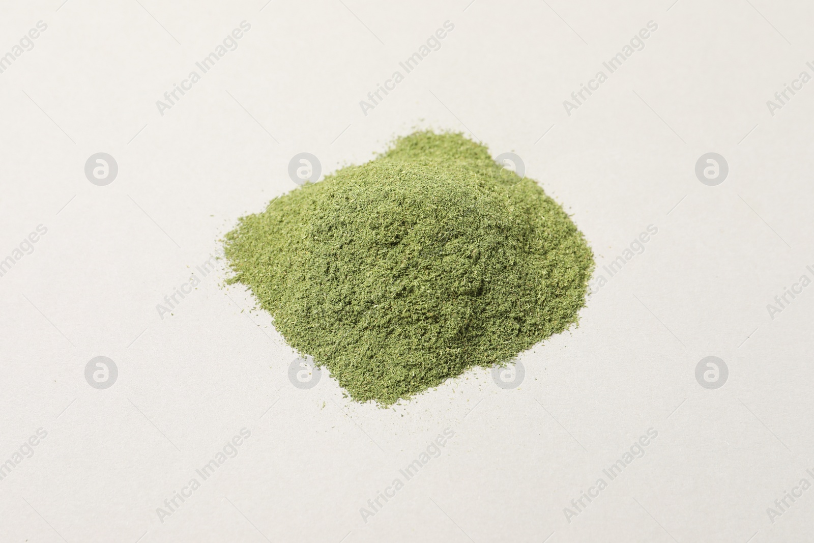 Photo of Pile of wheat grass powder on light table, closeup