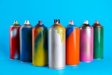 Used cans of spray paints on light blue background