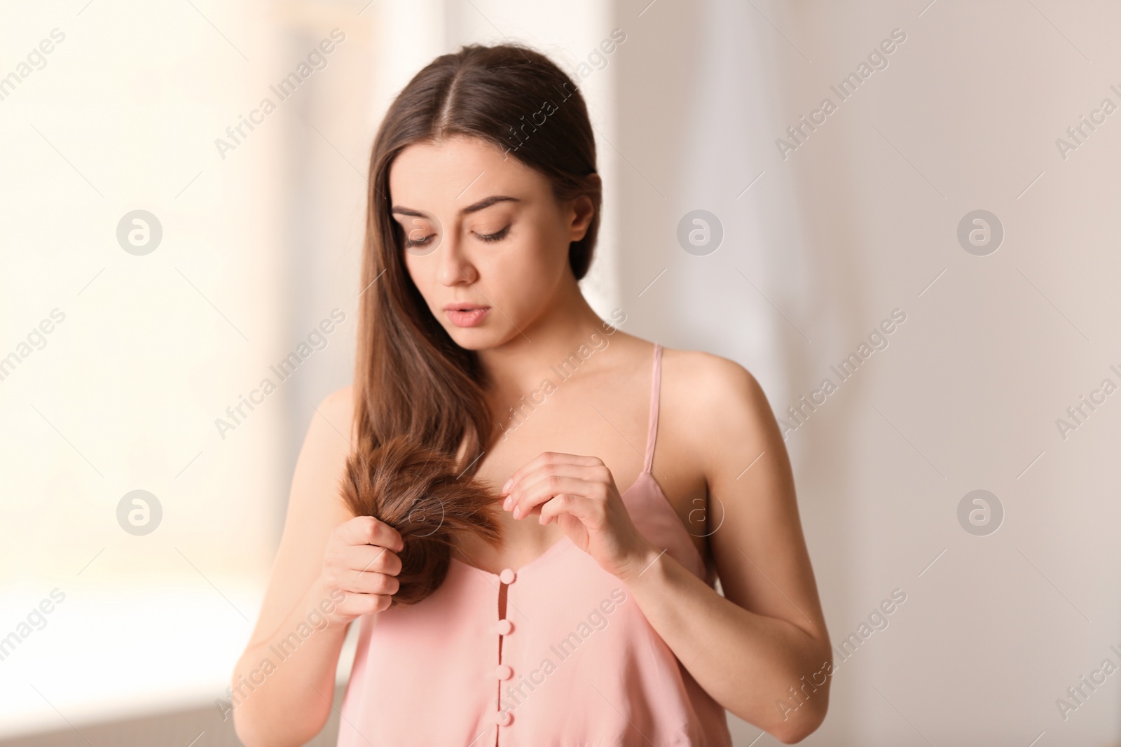 Photo of Woman with damaged hair on blurred background. Split ends