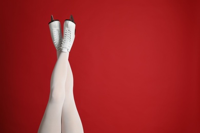Photo of Woman in elegant white ice skates on red background, closeup of legs. Space for text