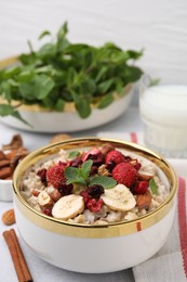 Photo of Delicious oatmeal with freeze dried berries, banana, nuts and mint on white table