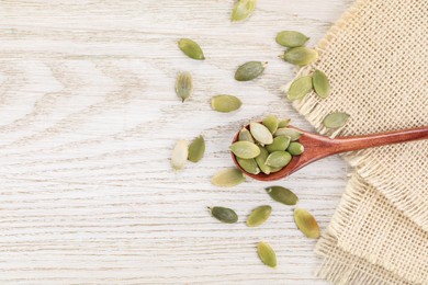 Photo of Spoon with peeled seeds on light wooden table, flat lay. Space for text