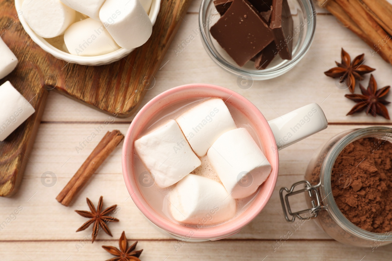 Photo of Tasty hot chocolate with marshmallows and ingredients on white wooden table, flat lay