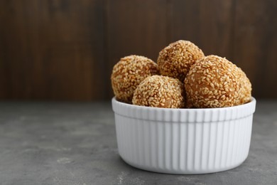 Photo of Bowl of delicious sesame balls on grey table, closeup. Space for text