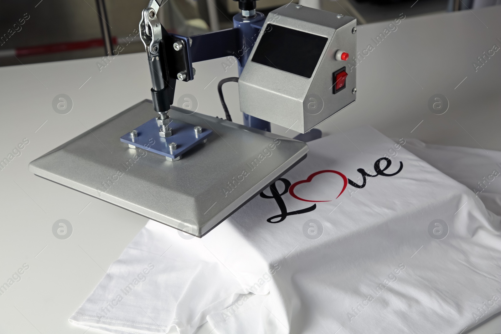 Photo of Printing logo. Heat press with t-shirt on white table