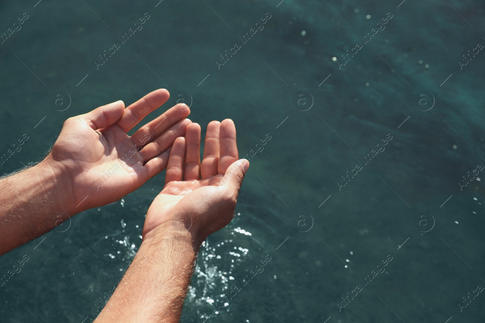 Photo of Man taking pure water from river, closeup. Nature healing power