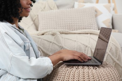 Woman using laptop on pouf at home, closeup