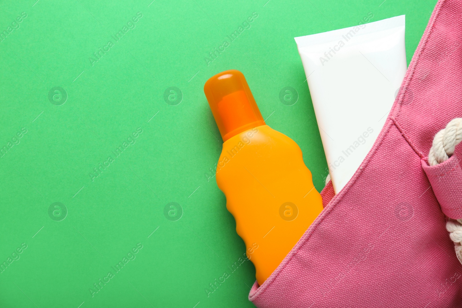Photo of Suntan products in bag on green background, flat lay. Space for text