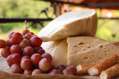 Photo of Delicious cheese, bread and ripe grape, closeup view