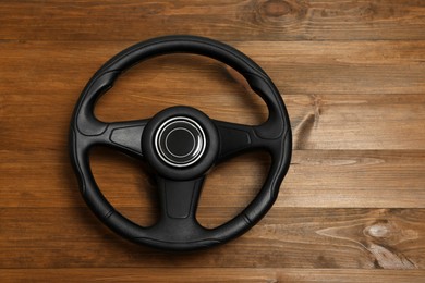 New black steering wheel on wooden table, top view. Space for text