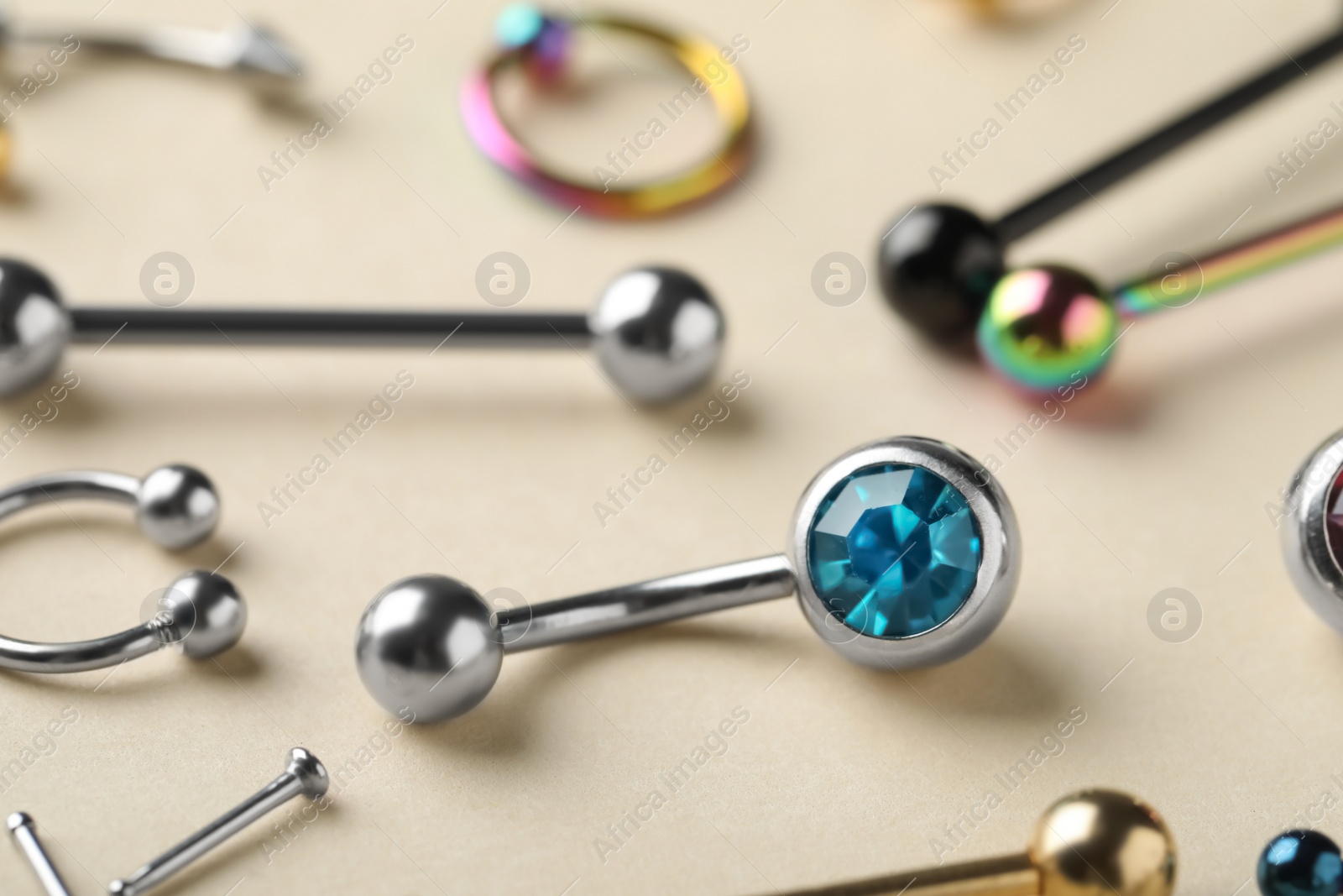 Photo of Stylish piercing jewelry on beige background, closeup