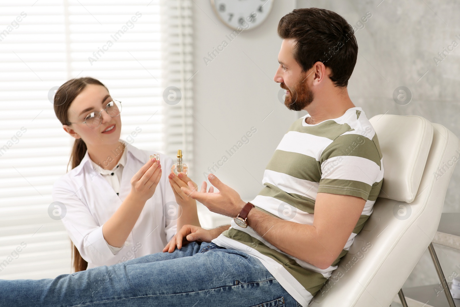 Photo of Doctor with educational model of dental implant consulting patient in clinic