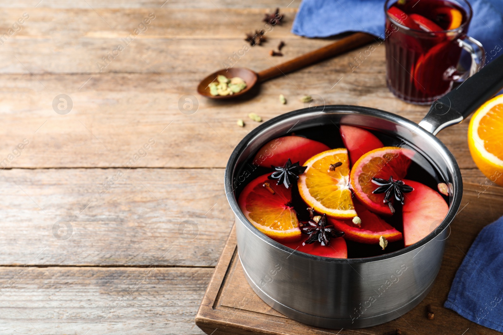 Photo of Delicious mulled wine and ingredients on wooden table. Space for text