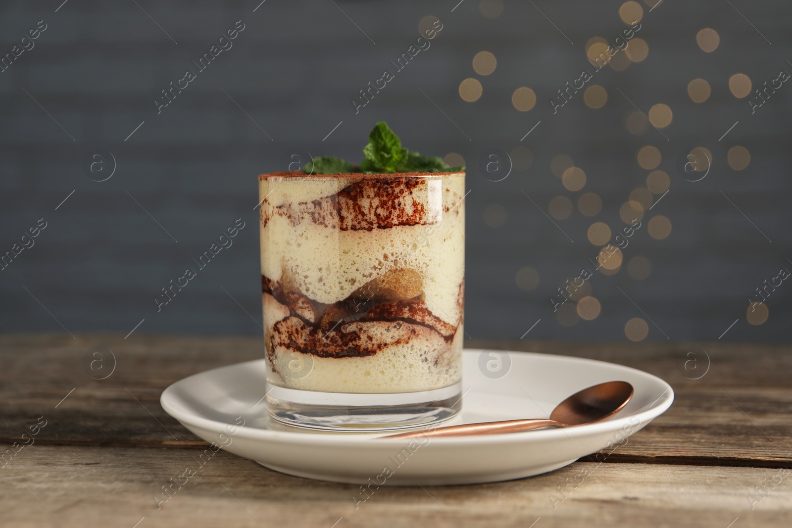 Photo of Tasty tiramisu and mint in glass on wooden table