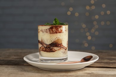 Photo of Tasty tiramisu and mint in glass on wooden table